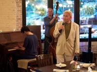 male singer in front of his band at a restaurant